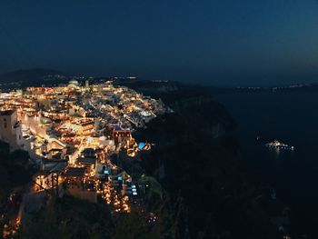 High angle view of illuminated townscape by sea against sky at night
