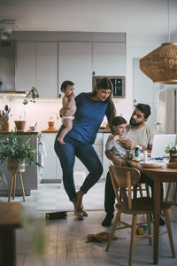 Parents with children taking online consultation on video call in kitchen at home