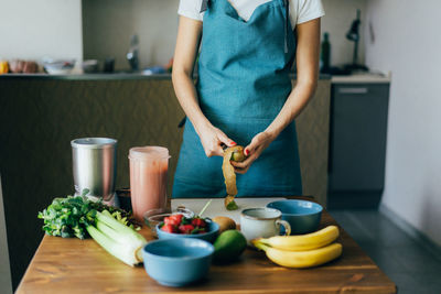 Midsection of woman standing on table at home