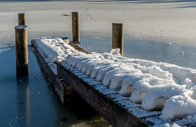 High angle view of wooden posts on snow covered pier