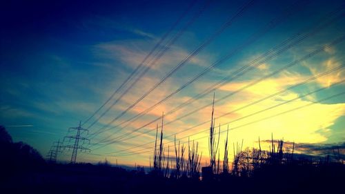 Low angle view of electricity pylon against cloudy sky