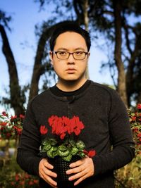 Portrait of young man standing by flowering plant