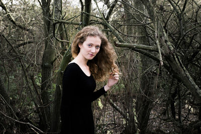 Portrait of beautiful woman standing against trees in forest