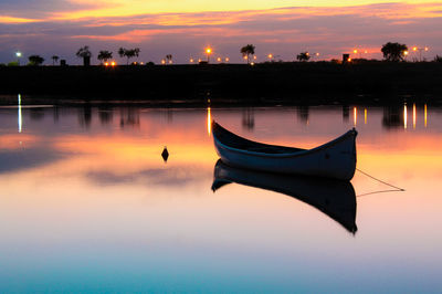 Boat moored in lake against sky during sunset