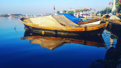 Boats moored at harbor against blue sky