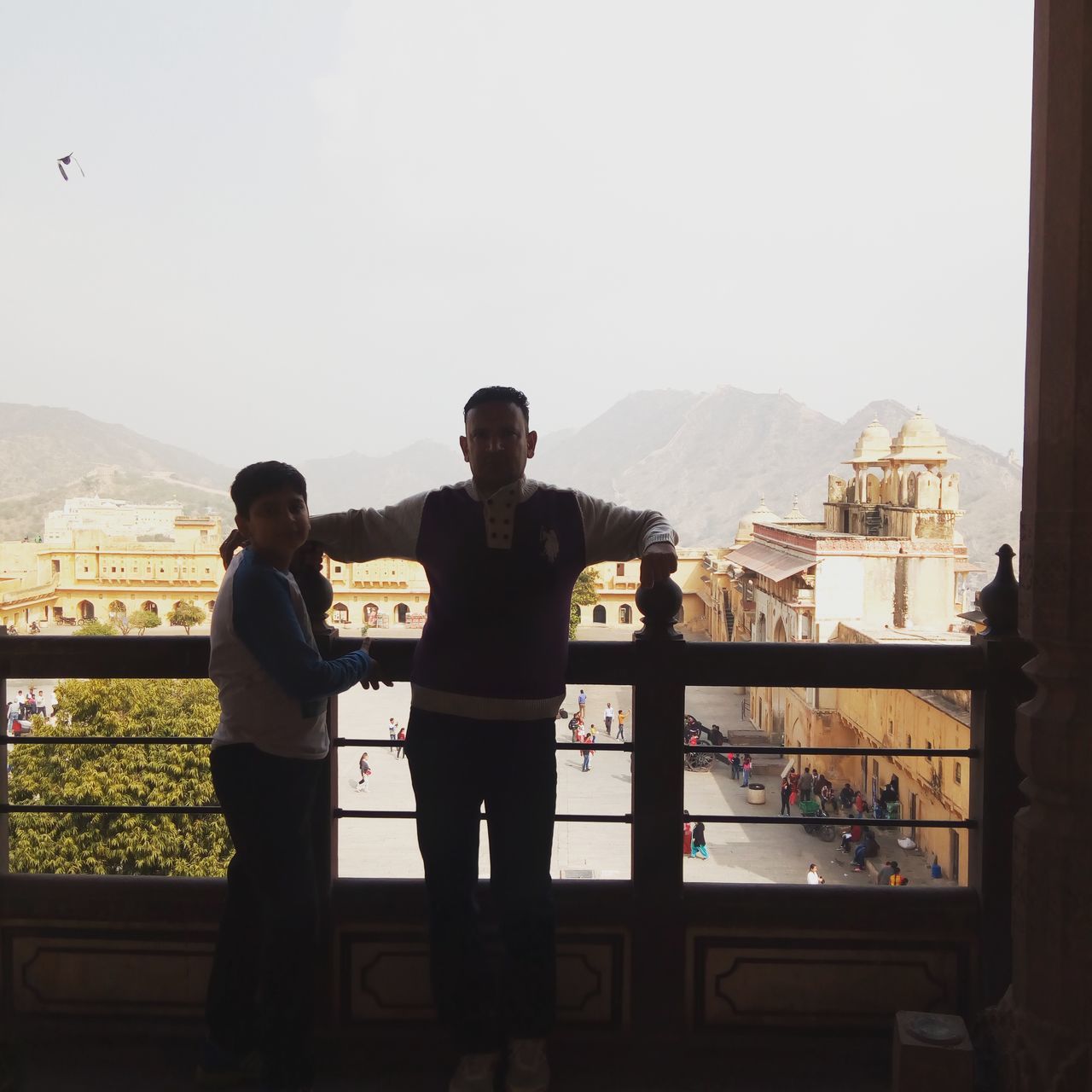 MEN STANDING BY RAILING AGAINST SKY