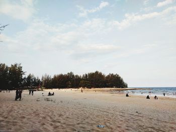 Group of people on beach against sky