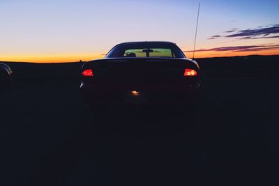 Car on landscape against sky during sunset