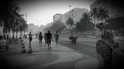 People walking on sidewalk by road in city at copacabana