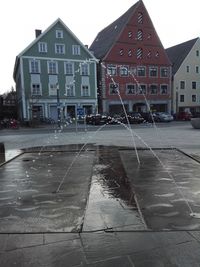 Wet street by buildings in city during rainy season