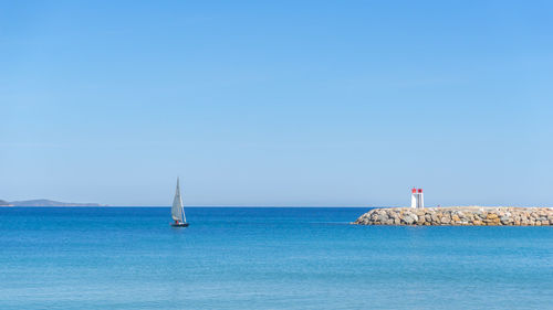 Sailboat in sea against clear blue sky