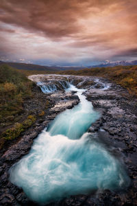 Scenic view of waterfall against sky during sunset