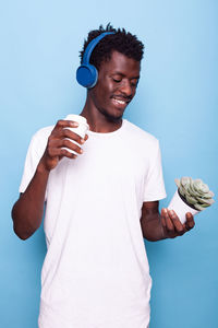Young man holding camera against blue background