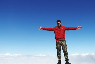 Low angle view of man standing against blue sky