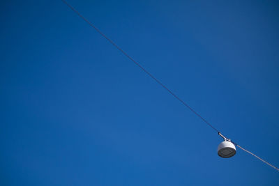 Low angle view of lamp hanging against clear blue sky