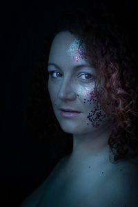 Close-up portrait of woman wearing mask against black background