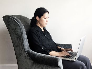 Young woman using mobile phone while sitting on seat