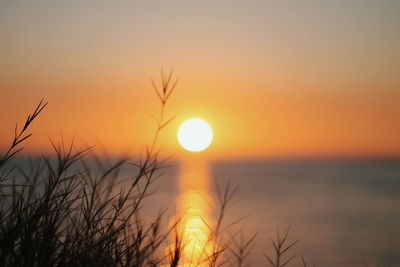 Close-up of sun in sea against sky during sunset