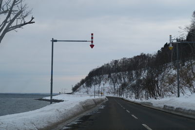 Road amidst snow covered landscape against sky