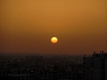 Silhouette buildings against romantic sky at sunset