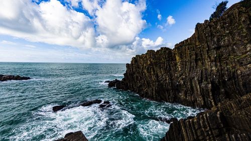 Rock formation by sea against sky