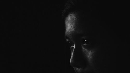 Close-up of young man against black background