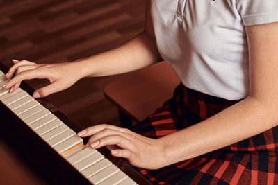 Asian high school student sitting at the piano