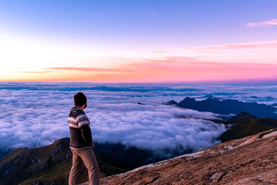 Man looking at view against dramatic sky during sunset