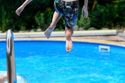 Low section of man jumping in swimming pool