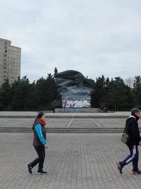 Full length of boys on footpath in city against sky