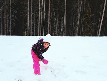 Girl playing with snow against trees