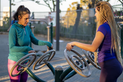 Mother and daughter are working out at the outside gym and having healthy and active lifestyle