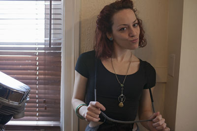 Portrait of young woman holding mobile phone at home