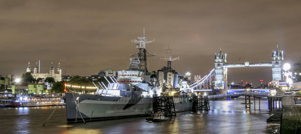 Illuminated boats moored in city at night