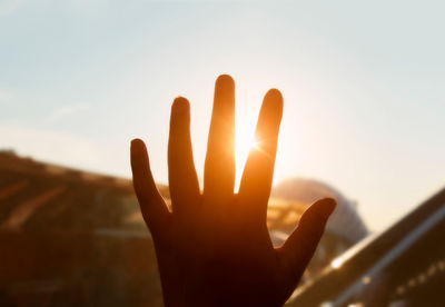 Close-up of hand against sky during sunset