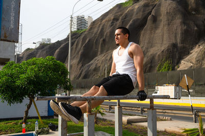 Full length of young man sitting on wall