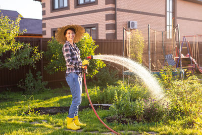 Full length portrait of smiling woman in yard