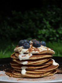 Stack of breakfast pancakes in the sun. topped wi the yoghurt, blueberries and cocoa powder.