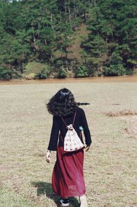 Rear view of woman walking on field