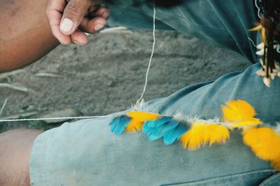 Midsection of man wearing jeans with feathers