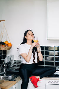 Full length of a beautiful young woman drinking glass