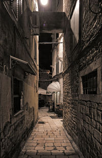 Narrow alley amidst buildings in city at night