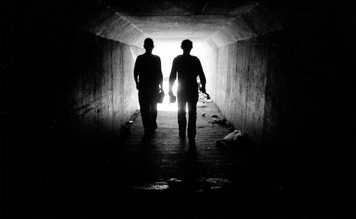 Silhouette people walking in illuminated tunnel