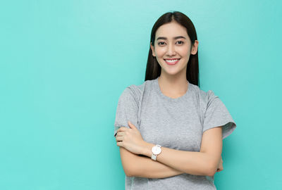 Portrait of smiling young woman against blue background