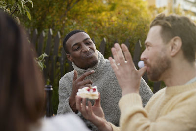 Smiling men eating cake in garden