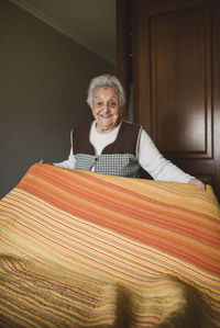 Senior woman putting fresh sheets on a bed