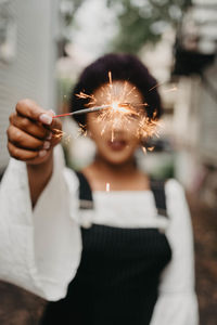 Midsection of woman holding sparkler at night