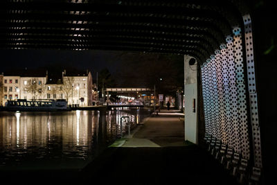 Illuminated buildings by river in city at night