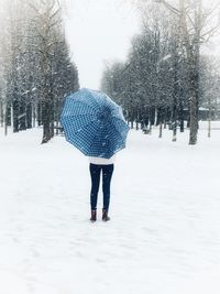 Rear view of woman walking on snow covered field