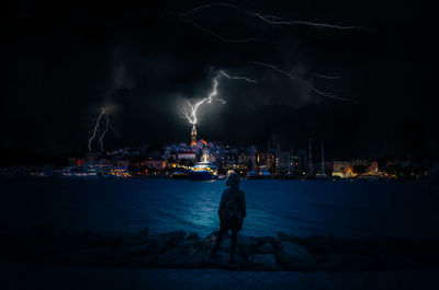 Panoramic view of illuminated city by sea against sky at night